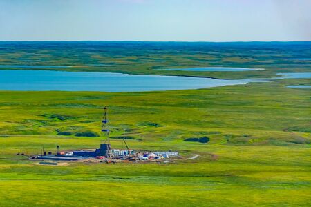 Drilling rig and equipment at an oil field in the northern tundra. Top view from a helicopter. Green...