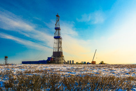 The sparse vegetation of the northern tundra at the beginning of winter in the Arctic. In the background is a drilling rig for oil and gas drilling.のeditorial素材