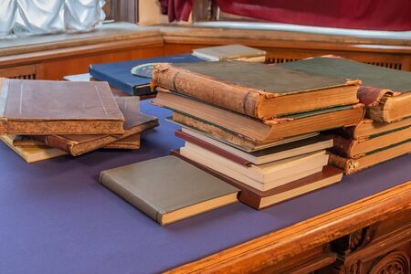 Shabby old books stacked in a pile on an old table with a fabric surface. Blurred background.