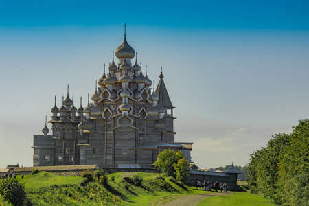 Landscape on the Kizhi island in Lake Onega on a summer sunny day. Wooden fishing boat in the foreground. In the background there is a vintage wooden mill, a temple and a churchの写真素材