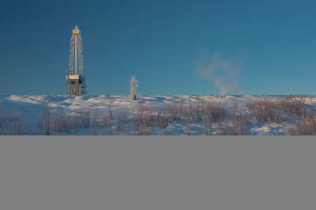Drilling oil and gas wells in the northern field. Polar frosty day. Winter forest-tundra landscape in the snow with a drilling rig. Beautiful skyの写真素材