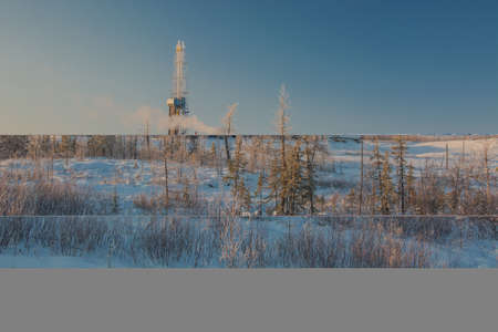 Drilling oil and gas wells in the northern field. Polar frosty day. Winter forest-tundra landscape in the snow with a drilling rig. Beautiful skyの写真素材