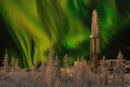 The rig and the northern landscape of the oil and gas field against the polar lights. Landscape with...