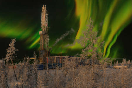 The rig and the northern landscape of the oil and gas field against the polar lights. Landscape with beautiful night sky in winter in the Arcticの写真素材