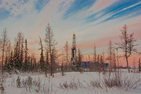 The landscape of the northern landscape of an oil and gas field with a drilling rig against the backdrop of a beautiful sky. Winter polar dayの写真素材