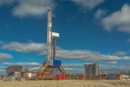 The design of a drilling rig for drilling wells in an oil and gas field in the far north. Oil rig with standing drill pipes and equipment against blue skyの写真素材