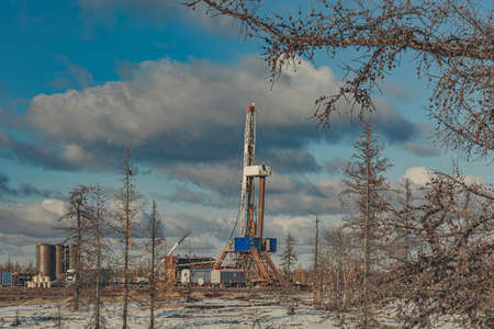 Winter landscape of an oil and gas field with a drilling rig and special equipment in the polar forest tundra. Ground is covered with snowの写真素材