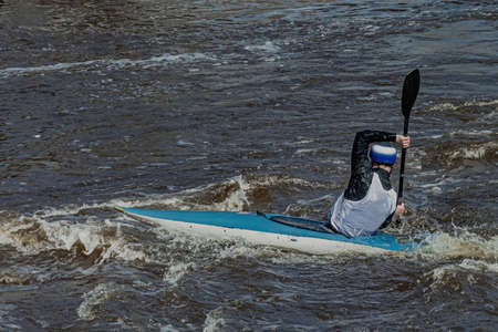 A series of images. Athletes in kayaks and kayaks conquer the stormy waters of the river. Dressed in waterproof clothes and helmets. They hold an oar in their hands. motion blurの写真素材