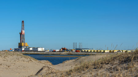 Drilling oil and gas wells in desert terrain. Sand hills, sparse vegetation. Beautiful sky. Infrastructure of the drilling rigの写真素材