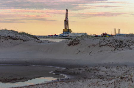 Drilling oil and gas wells in desert terrain. Sand hills, sparse vegetation. Beautiful sky. Infrastructure of the drilling rigの写真素材