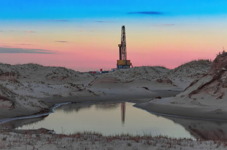 Drilling oil and gas wells in desert terrain. Sand hills, sparse vegetation. Beautiful sky. Infrastructure of the drilling rigの写真素材