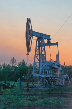 Oil production at the field. Extraction of oil from the reservoir using a rocking machine. The construction of the rocking machine. Summer. Beautiful sky and natureの写真素材