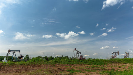 Oil production at the field. Extraction of oil from the reservoir using rocking machines. The construction of the rocking machine. Summer. Beautiful sky and natureの写真素材