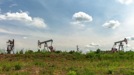 Oil production at the field. Extraction of oil from the reservoir using rocking machines. The construction of the rocking machine. Summer. Beautiful sky and natureの写真素材