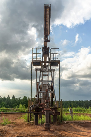 Oil production at the field. Extraction of oil from the reservoir using a rocking machine. The construction of the rocking machine. Summer. Beautiful sky and natureの写真素材