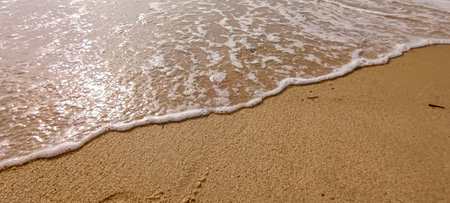 Sea foam flows along the sand at Pasir Panjang Beach, Singkawangの写真素材
