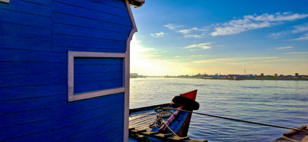 Traditional wooden boat bow with small white-framed windows in the cabin looks out to the horizon under a bright blue sky.の写真素材