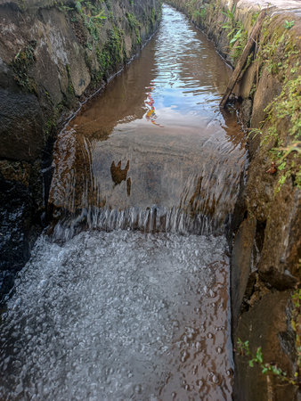 Irrigation ditch with stone walls and some plants growing on the sidesの写真素材