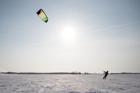 Anonymous person kiting with parachute in spacious snowy field. の写真素材