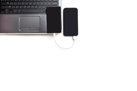 Black power bank and smartphone on computerの写真素材