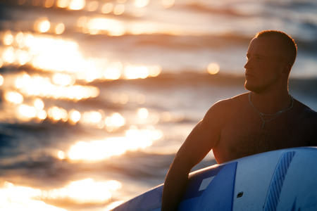Young man in sunset with paddleboardの写真素材
