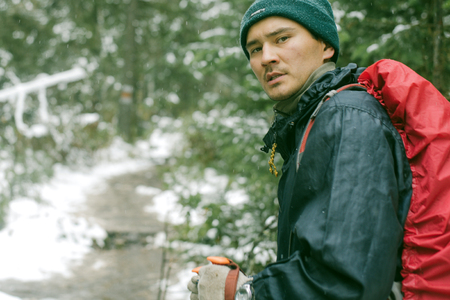 The man in the woods with the red backpack with a protective case