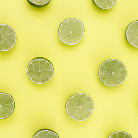 Background of limes split in half on yellow background