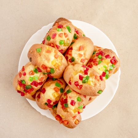 Cupcakes with candied fruits on a white plate on a paper surface