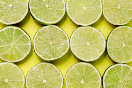 Background of limes split in half on yellow backgroundの写真素材