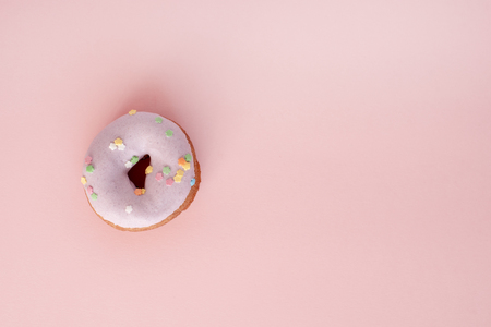A donut covered in purple frosting on pink surfaceの写真素材