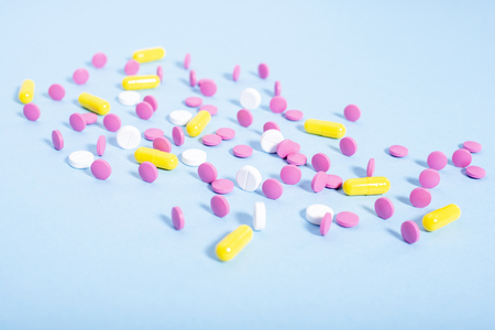 Pink and white pills, yellow and white capsules  on blue background