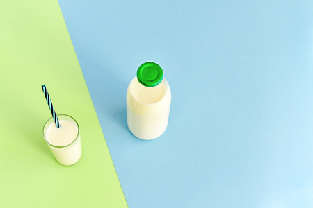 Milk in  glass bottle and transparent glass with straw on  blue-green backgroundの写真素材