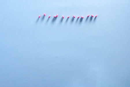 Pink pills in row on blue background