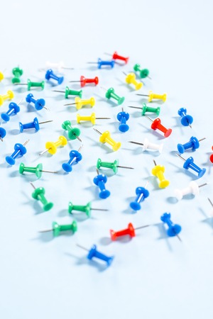 Multi-colored stationery buttons with needles on blue background