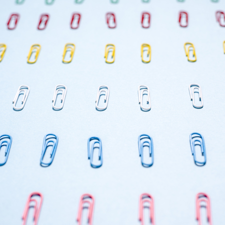 Multi-colored paper clips in row on blue backgroundの写真素材