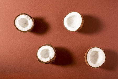 Four halves of coconut on brown background. Top viewの写真素材