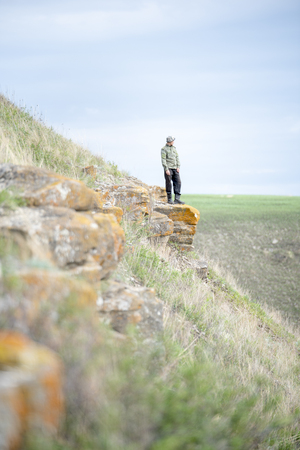 A man in uniform standing on a rock and looking into the distanceの写真素材