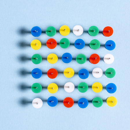Multi-colored stationery buttons on a blue background stacked needles up in a rowの写真素材