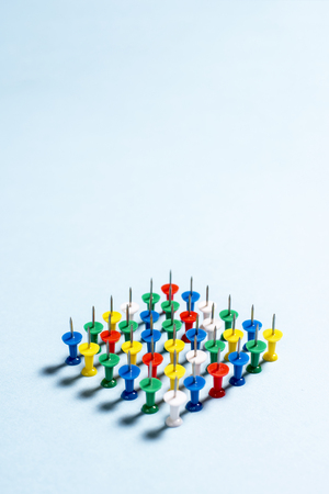 Multi-colored stationery buttons on a blue background stacked needles up in a rowの写真素材