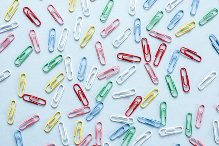 Multi-colored paper clips on blue background . Top view