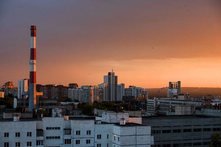 City landscape with chimney and multi-storey houses at sunsetの写真素材