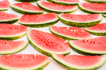 Background of red Slices of delicious juicy watermelon lying on a white tableの写真素材
