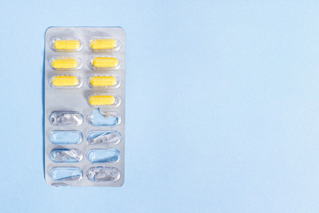 Yellow pills in packing on blue backgroundの写真素材