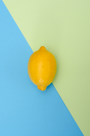 One yellow lemon on green-blue background. The view from the top.の写真素材