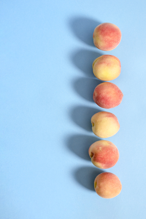 Whole ripe beautiful peaches on blue background with shadowsの写真素材