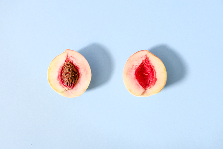 Ripe beautiful peach split in half. Visible the stone is. The background blue.