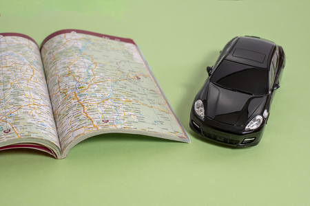 Black business class toy car and road map in book version on green backgroundの写真素材