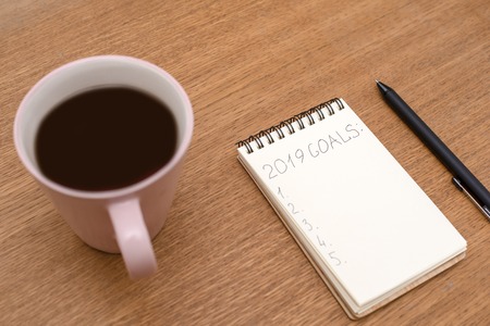 Notebook with inscription Goals and Cup of coffee on the wooden surface