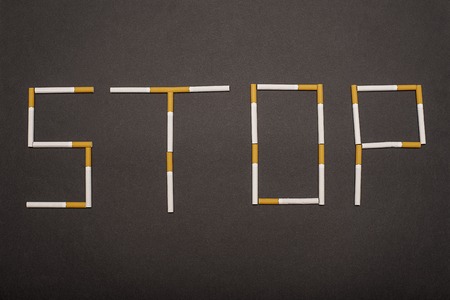 The inscription "STOP" lined with cigarettes on black backgroundの写真素材