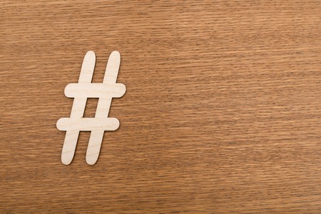 Hashtag sign made of wooden material on wooden background. Top viewの写真素材